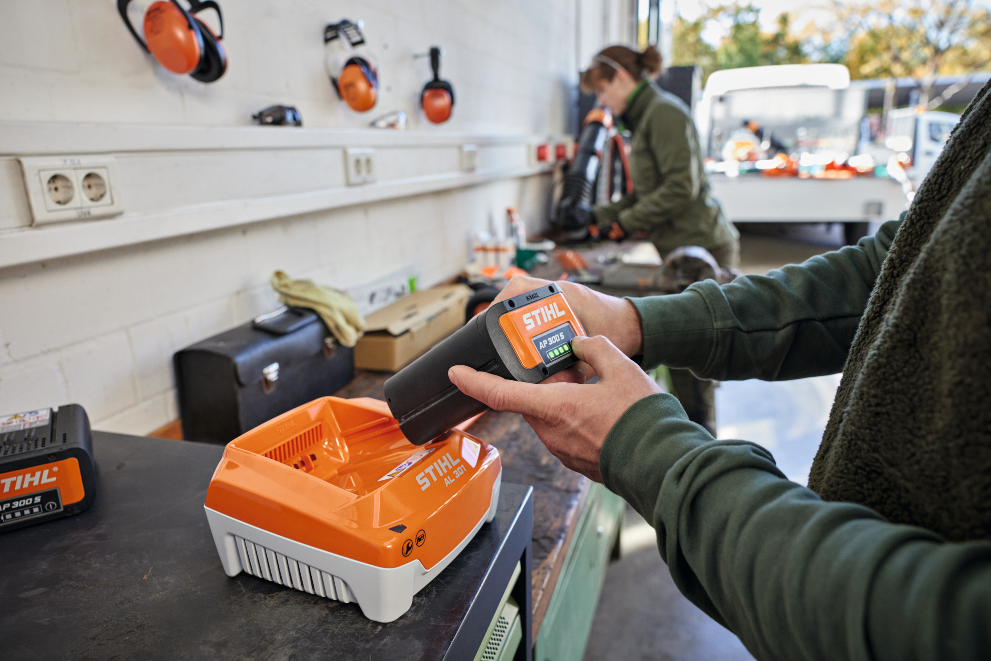 Uma pessoa insere uma bateria STIHL AP 300 S em um carregador rápido STIHL AL 301