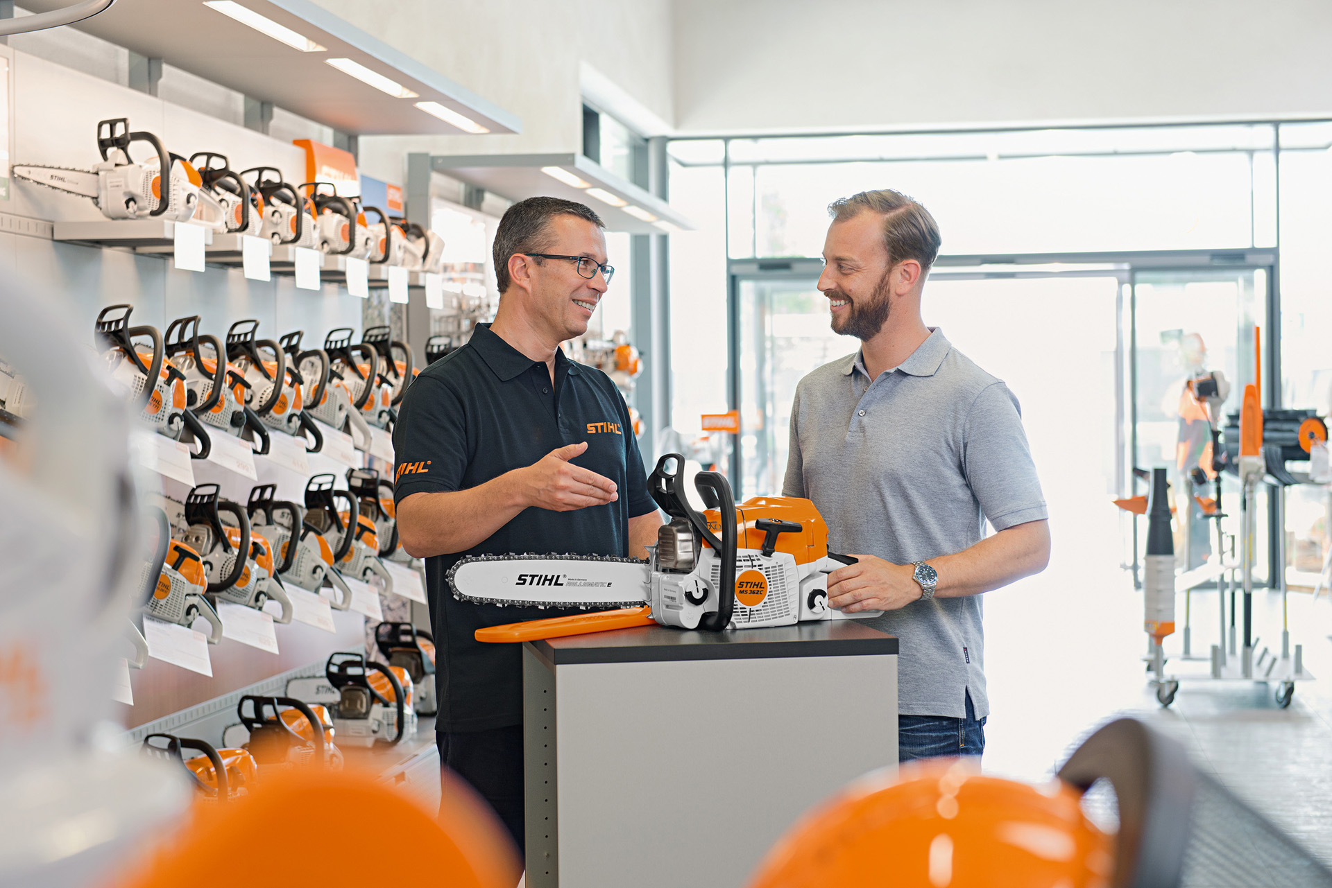 Um revendedor STIHL aconselha um jovem durante a compra de uma motosserra STIHL.