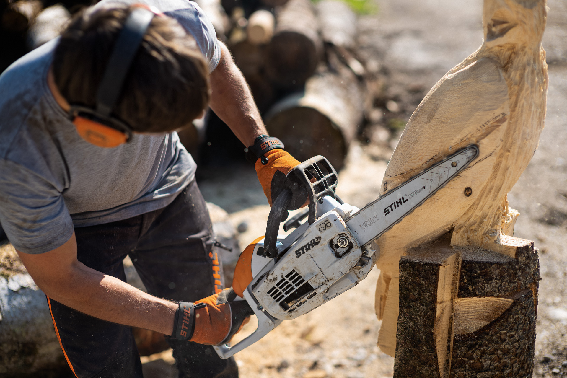 Um homem esculpe uma coruja num tronco de madeira com uma motosserra STIHL