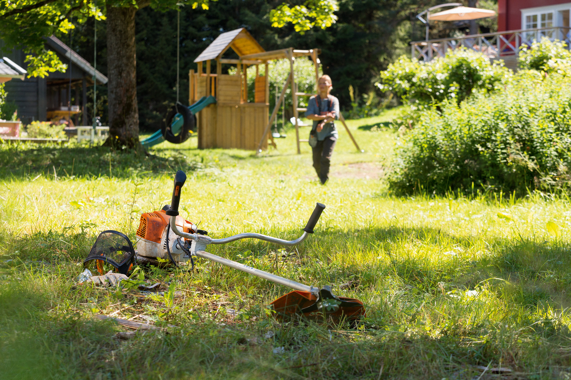 Uma roçadeira STIHL FS&nbsp;240 na relva e, em segundo plano, um homem prepara-se para a manutenção