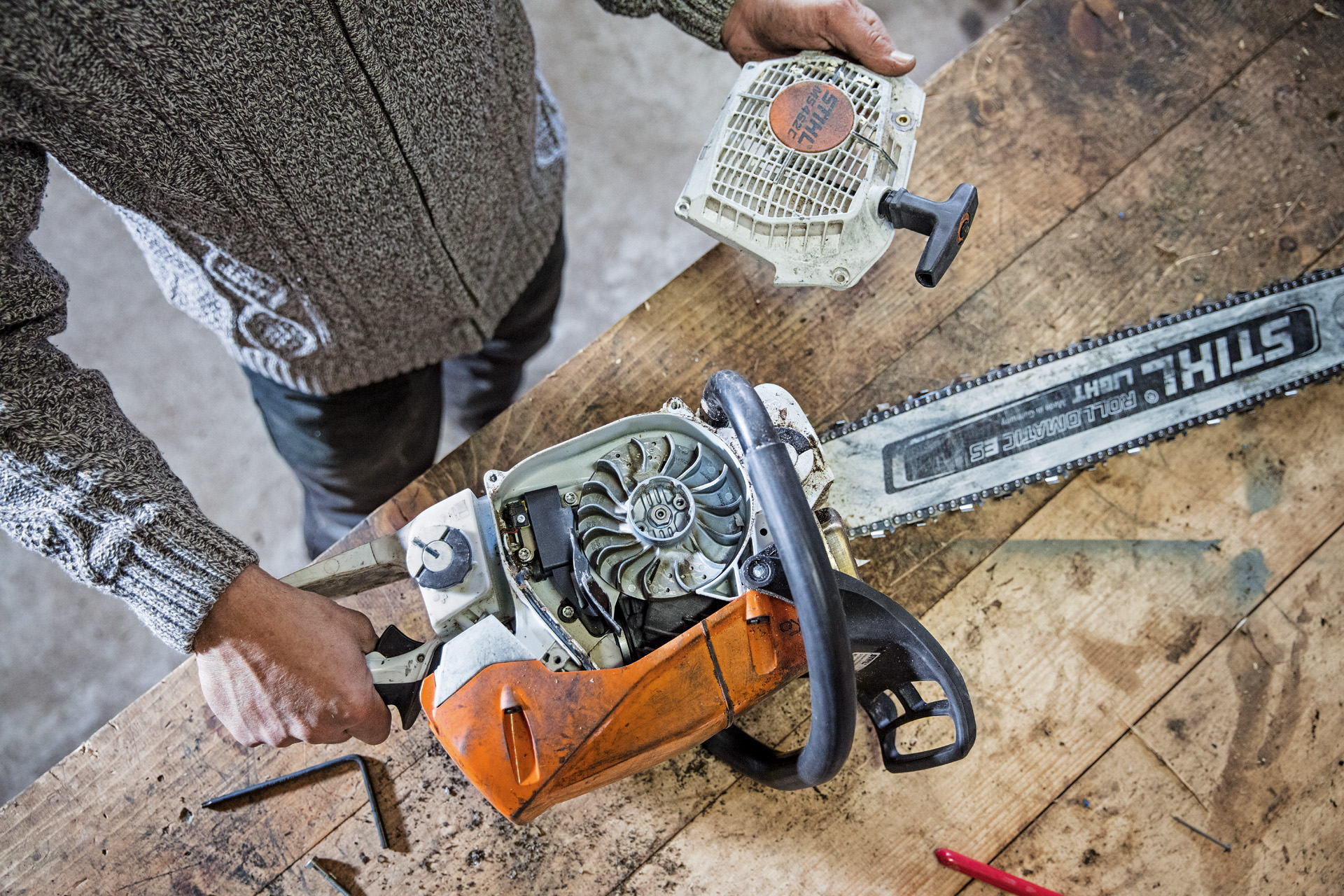 Uma pessoa faz a manutenção de uma motosserra a gasolina STIHL MS 462 C-M numa bancada de trabalho