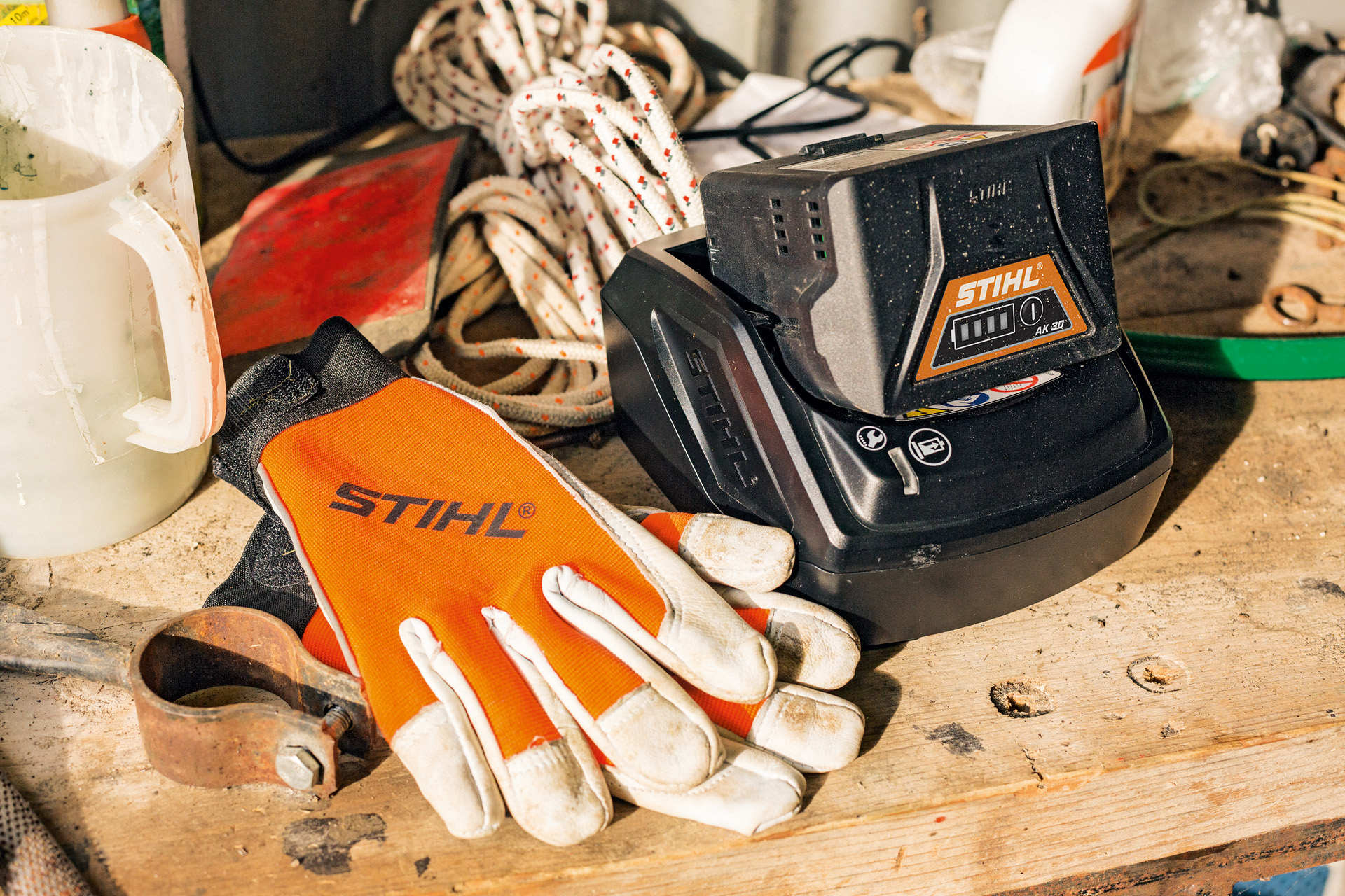 Carregamento de baterias de ions de lítio da série AK junto a luvas e ferramentas de trabalho STIHL