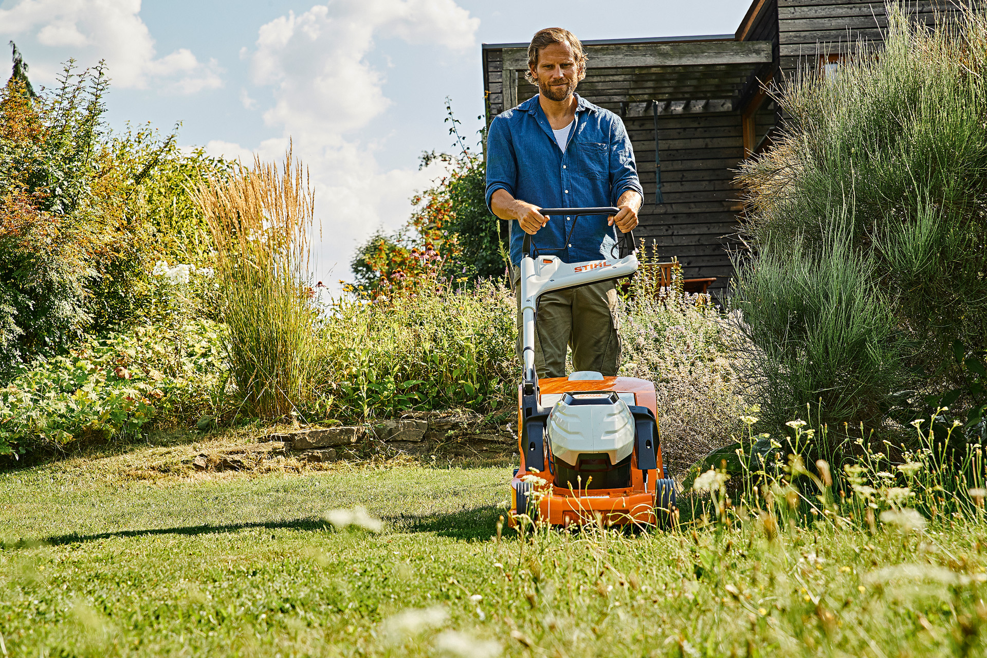 Um homem aplica as dicas dos cuidados com a grama no verão com um cortador de grama a bateria STIHL RMA 448 P-C