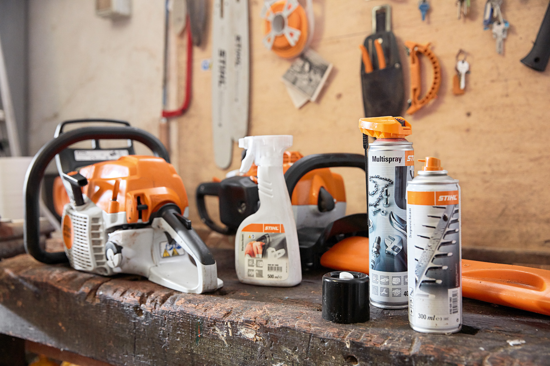 Uma bancada com vários produtos STIHL para limpar uma motosserra: Varioclean, Multispray e solvente de resina Superclean